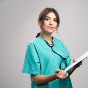 Confident female healthcare professional in scrubs holding a clipboard and stethoscope, representing a qualified specialist in psychiatry.
